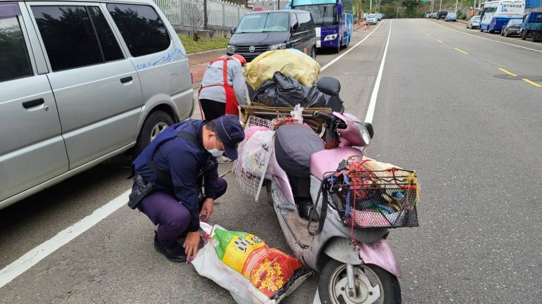 圖片說明：蘆竹分局警備隊員警丁嘉慶協助老婆婆撿拾散落的資源回收物品並綑牢。(記者宋紹誠翻攝）