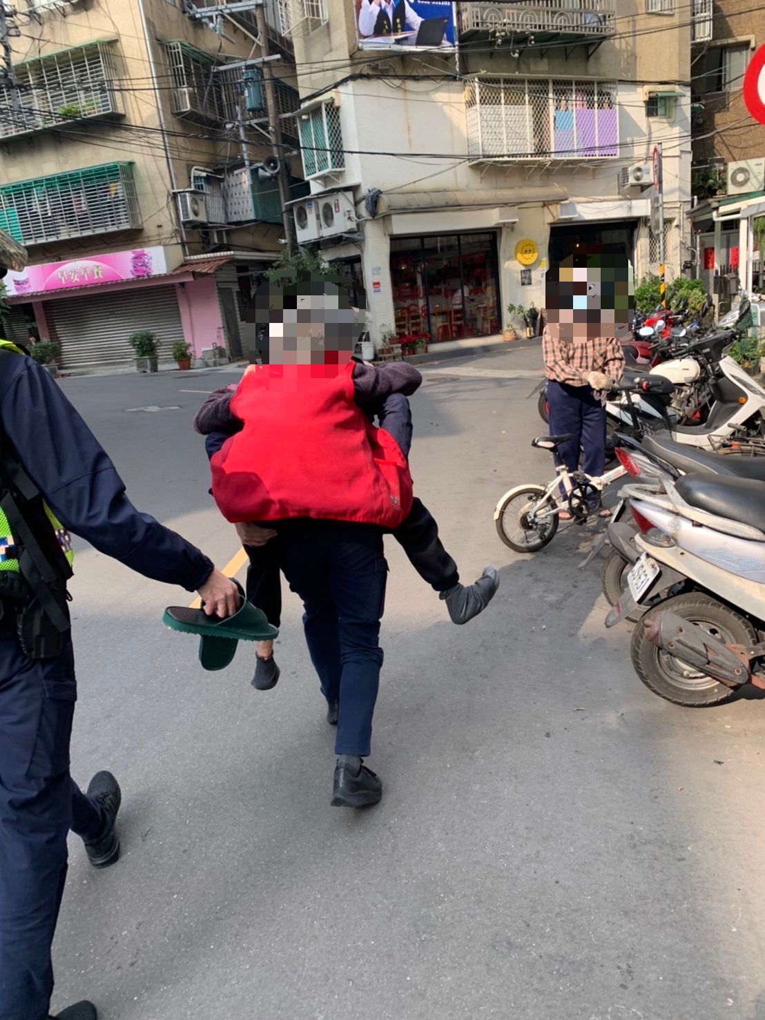 圖片說明：江翠派出所警員李祁彥、蔡宗儒、王宏瑋合力將老奶奶攙扶背返住家。(記者林鈞澤翻攝)