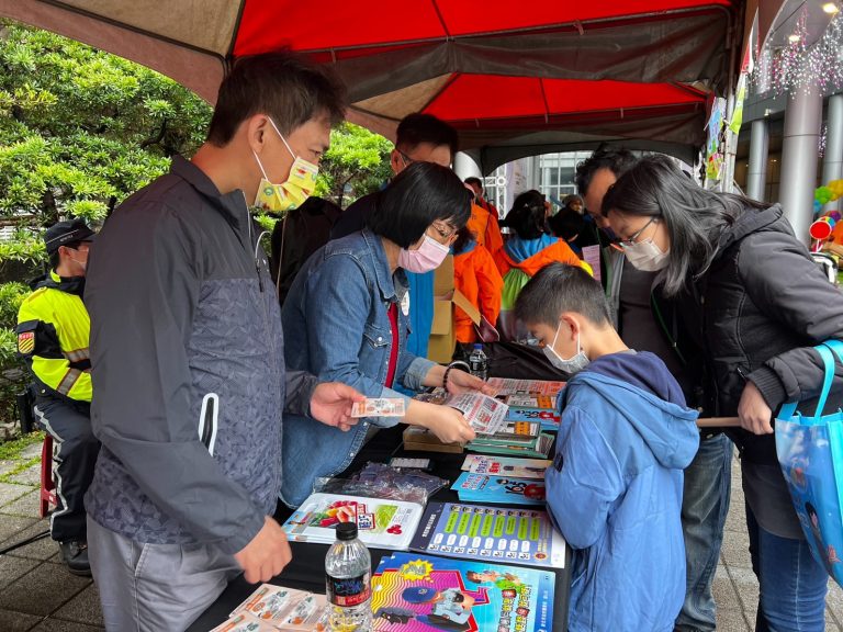圖片說明：海山分局員警配戴警察大頭娃娃設攤宣導，藉由有奬徵答提醒民眾注意預防走失、自我保護、防範各類詐騙手法。(記者林艷林翻攝)