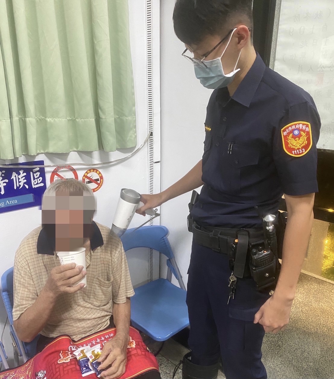 圖片說明：樹林暖警親自幫老翁吹乾淋濕衣物。（記者徐煜勝翻攝）