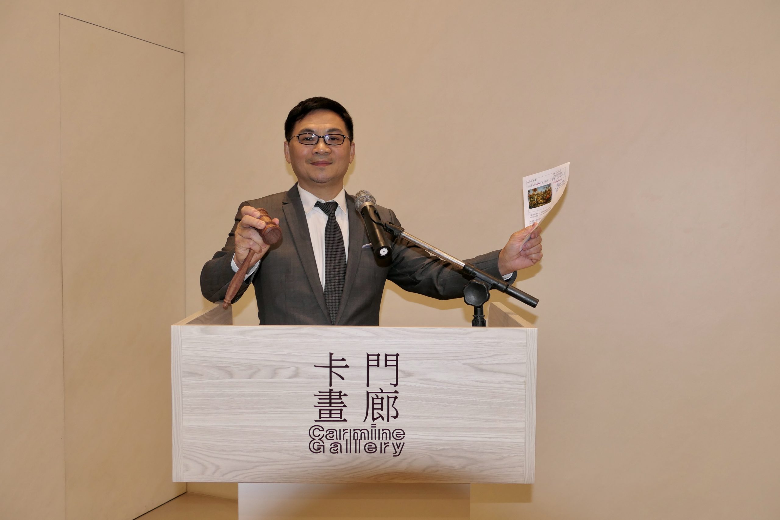 卡門畫廊董事長林辰陽擔任拍賣官，右手所持為特製花梨木拍賣槌。（記者馬治薇攝）