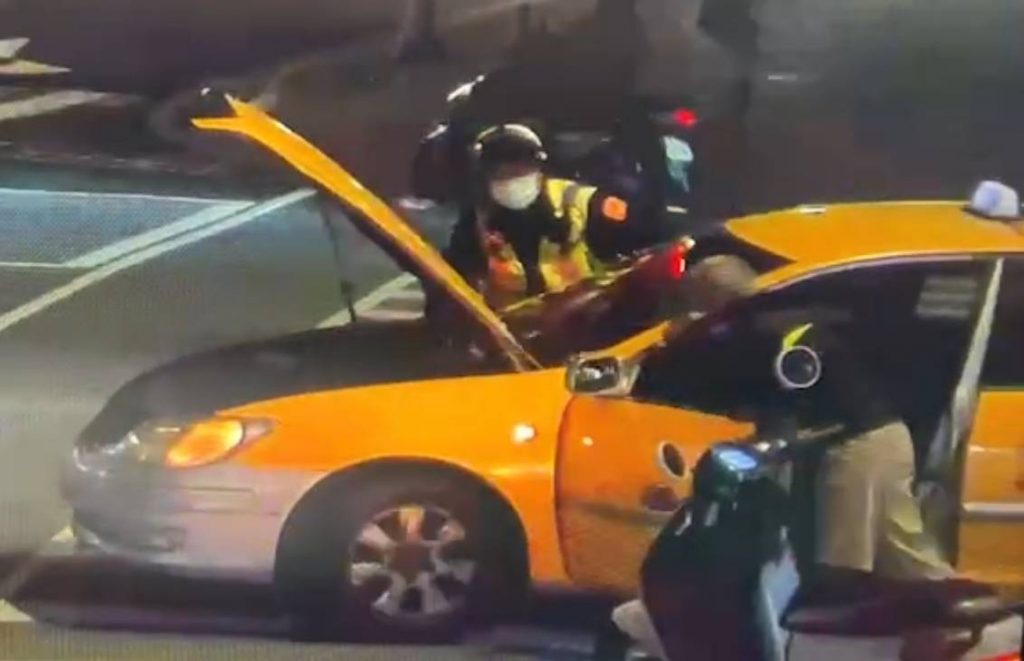 警員協助運匠將拋錨小黃推至路邊。(記者林金聖翻攝)