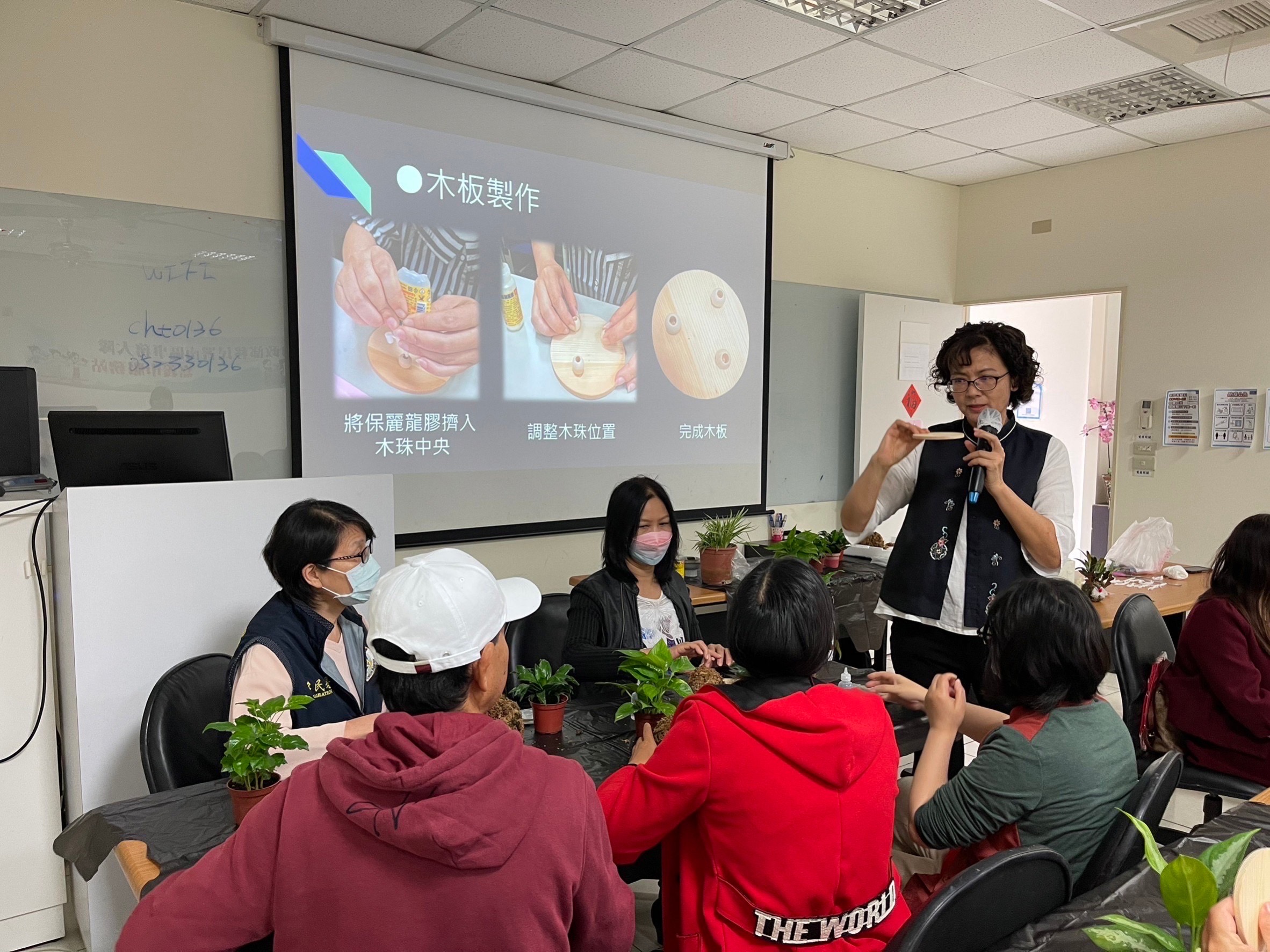 嘉義縣市中小企業榮譽指導員協進會會長張麗梅(站立者)講解如何手作聖誕苔球。(記者 張艷君翻攝)