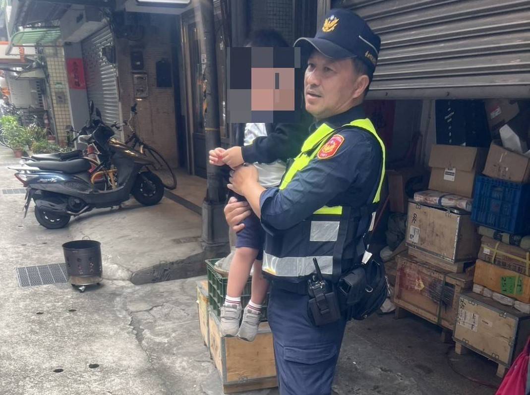 赤峰街巷弄內,一名三歲男童因與父親走散而獨自徘徊,建成派出所巡佐黃榮章溫柔安撫男童。(記者黃荷琇 翻攝)