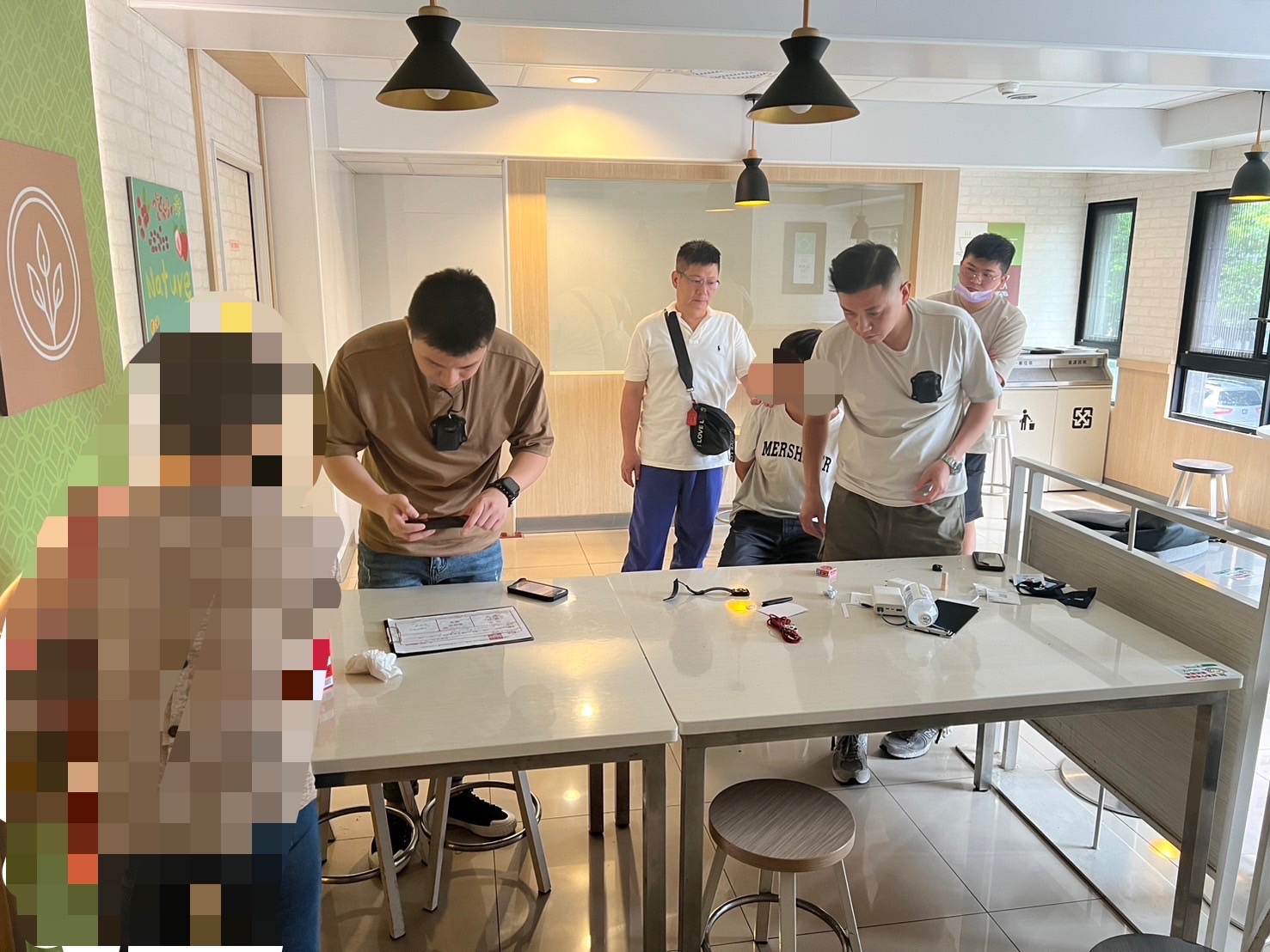 趁詐騙集團車手出面取款時，林口警方當場壓制逮捕，現場查扣偽造工作證、手機、現金憑證等贓證物。（記者黃荷琇 翻攝）