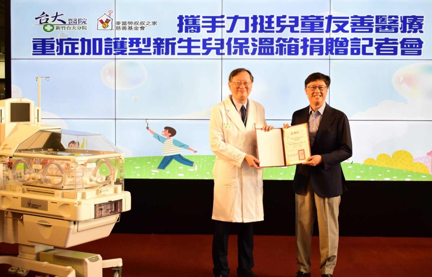 新竹臺大分院院長余忠仁（左）代表受贈，感謝麥當勞叔叔之家慈善基金會董事長李昌霖（右）捐贈兩台重症加護型新生兒保溫箱，攜手提升早產與重症新生兒照護品質。（圖/記者張家燁翻攝）