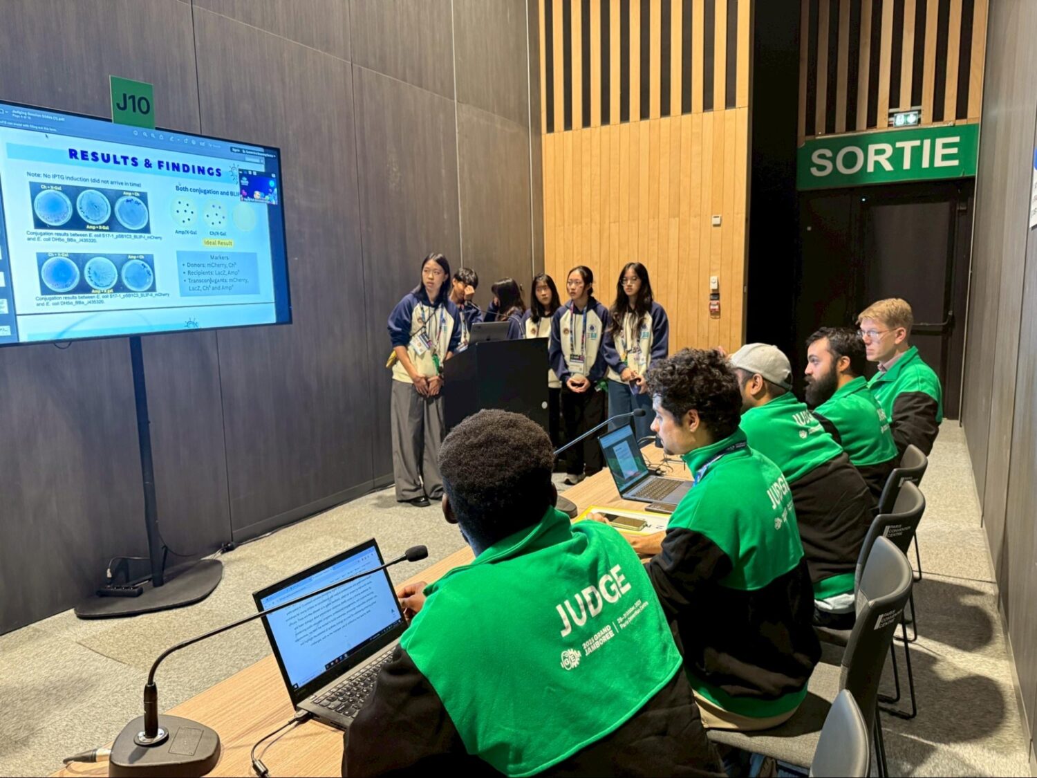 HIA-Taiwan PlasMission 團隊於 iGEM Grand Jamboree 現場向國際評審進行研究簡報，展現自主實驗成果與合成生物學應用構想。（圖/記者張家燁翻攝）