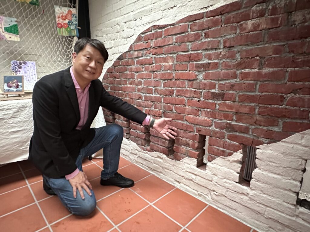 香山樂齡中心葉國文主任於香村豬寮空間內,向外界介紹保留並活化既有豬寮磚牆結構的設計巧思,展現農村再生中結合歷史記憶與空間美學的改造成果。(圖/記者林照東攝)