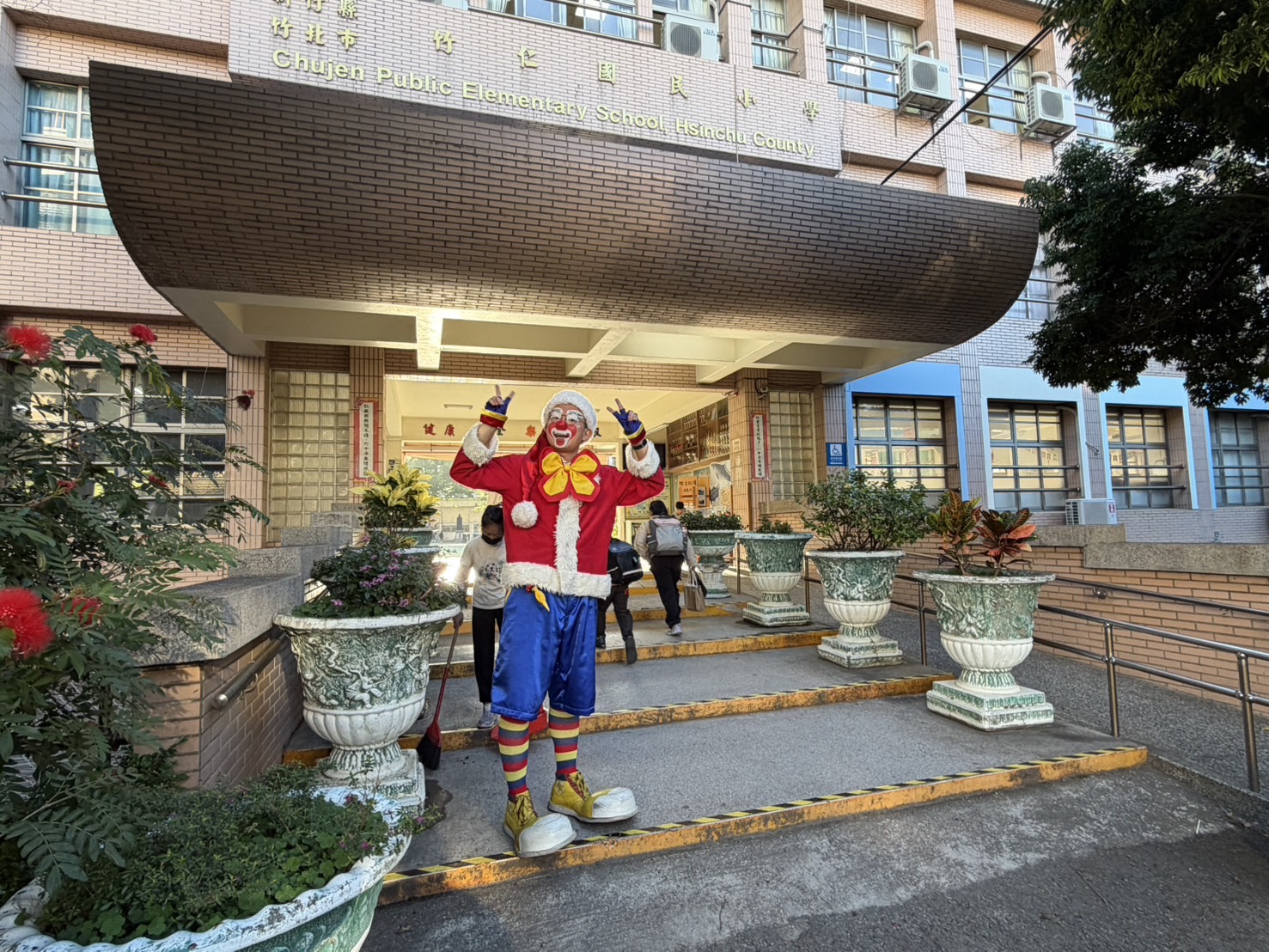 聖誕節氣氛滿滿，魔術冠軍菲力以逗趣造型現身竹仁國小校門口，熱情迎接師生，為校園揭開歡樂聖誕活動序幕。（圖/記者張家燁拍攝）