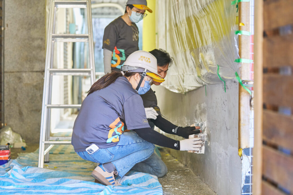 刨除剝落的牆面舊漆後進行丕土，以便後續上漆時的牆面平整。(圖／遠雄文教公益基金會 提供)