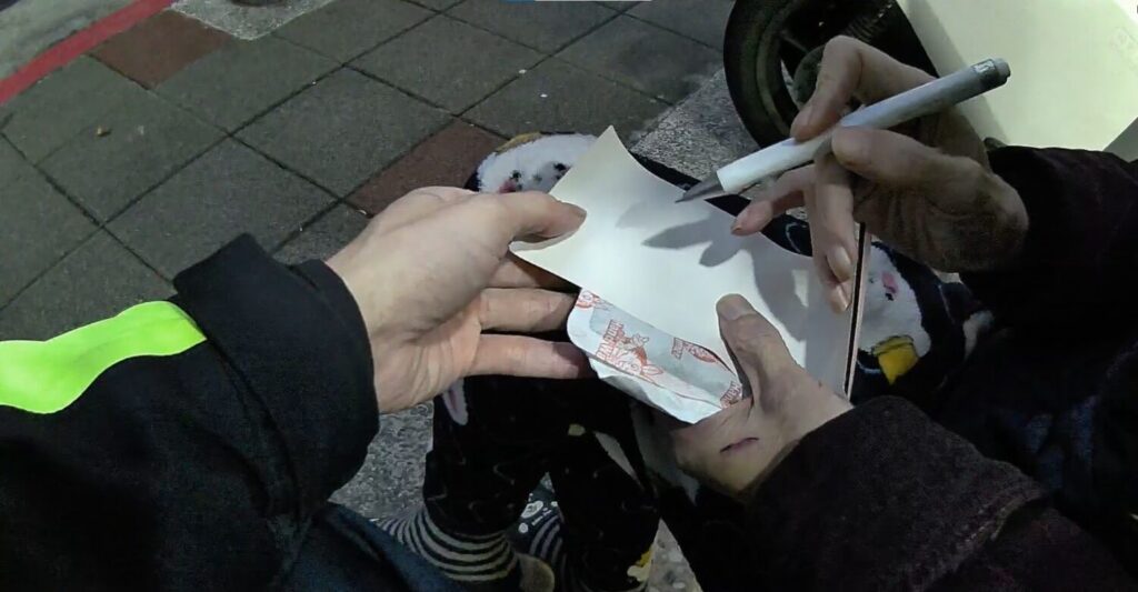 員警嘗試讓老翁書寫名字。(圖/記者薛秀蓮 翻攝)