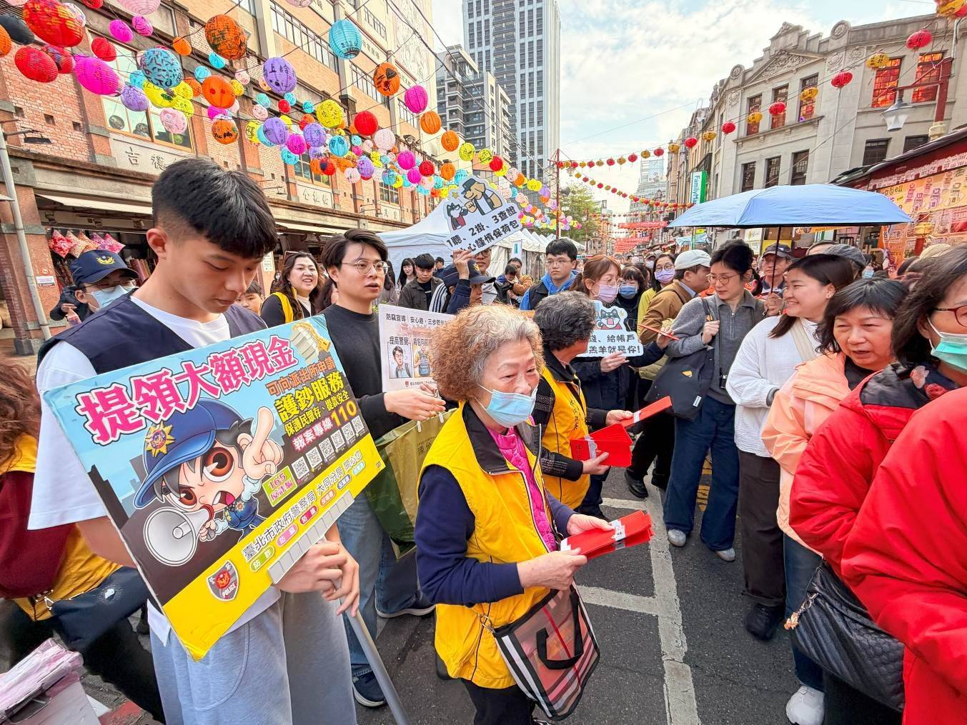 員警、義警及志工團隊深入人群，發放紅包袋宣導品，透過互動方式向民眾宣導防竊、識詐、護鈔及交通安全觀念。(圖／記者戴昱弘 翻攝）