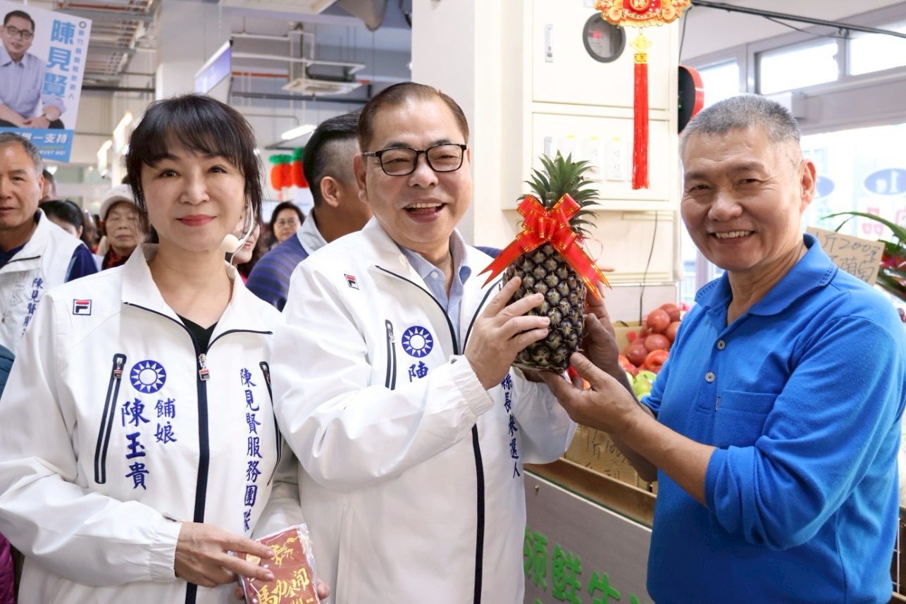 新竹縣長參選人陳見賢於市場拜年時，攤商送上象徵「旺來」的鳳梨祝福好彩頭，現場氣氛熱絡。（圖／記者林照東翻攝）