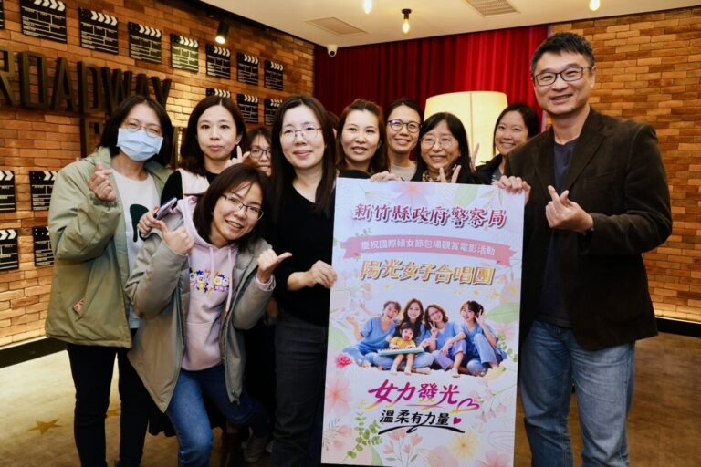 新竹縣警察局局長林建隆與女性同仁手持《陽光女子合唱團》活動看板合影，透過電影觀賞活動向女性同仁致上婦女節祝福。（圖／新竹縣警察局提供）