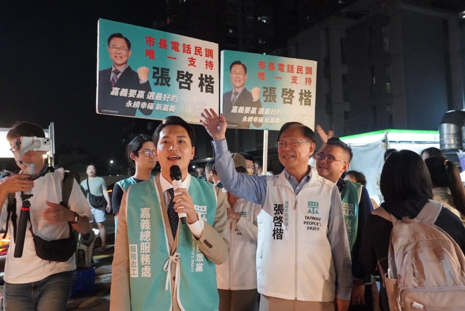 國民黨立委羅庭瑋南下陪同張啓楷逛夜市，穿上助理背心拿起麥克風就為張啓楷助講，兩人好交情表露無遺。(圖／民眾黨嘉義市黨部)