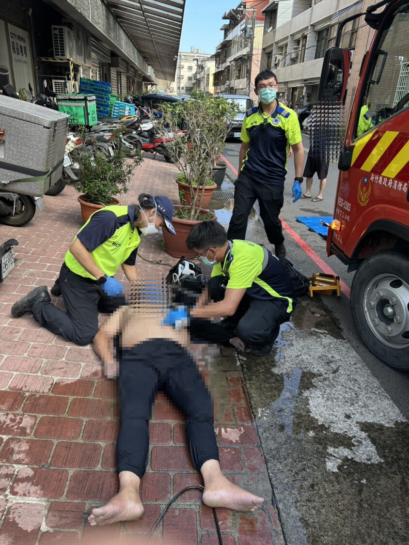新竹縣政府消防局救護人員於竹東鎮民族路化糞池工安意外現場，緊急替昏迷工人實施急救處置，並持續進行生命徵象監測。（圖／記者張家燁翻攝）