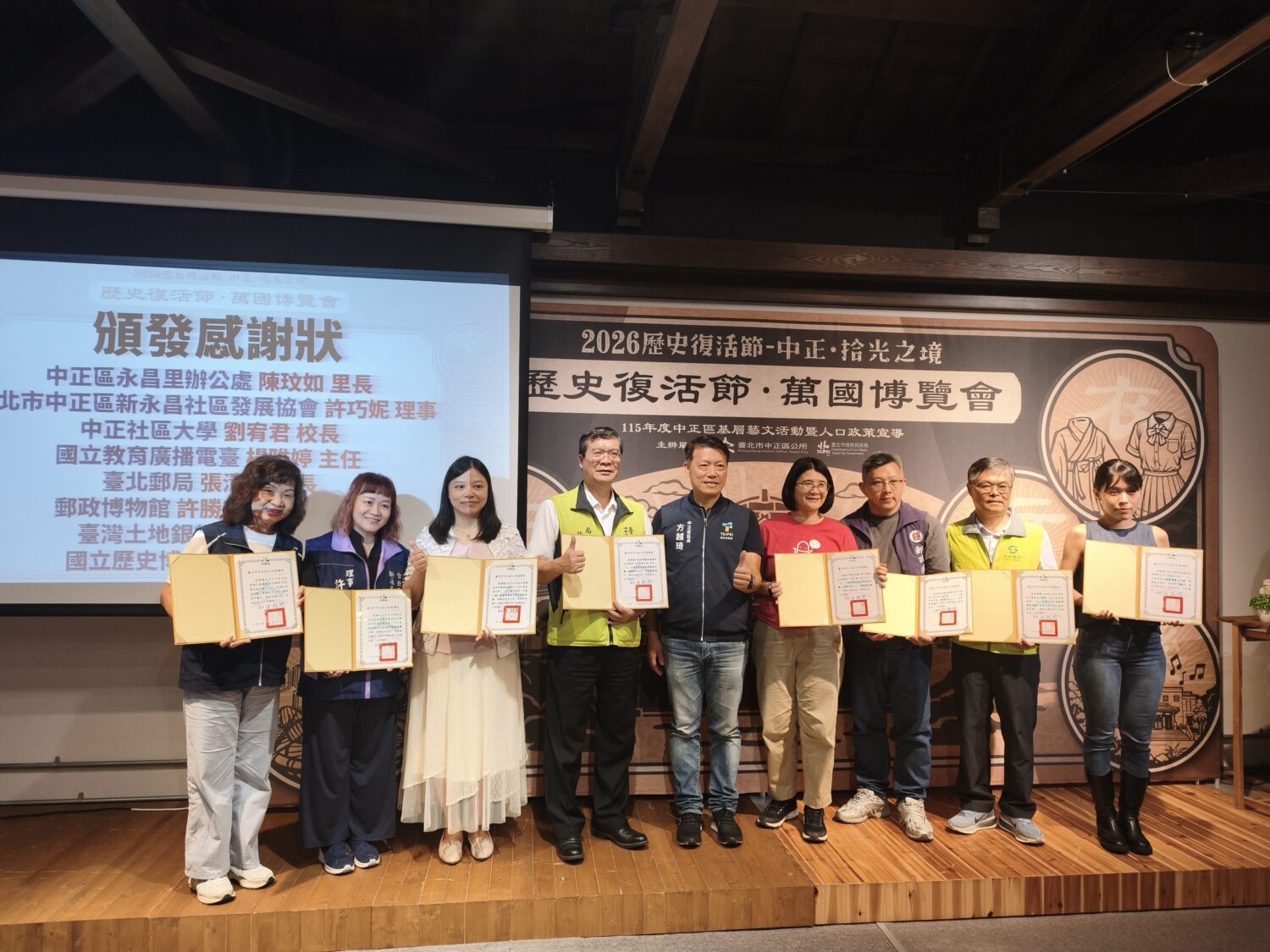 土地銀行「80周年檔案展」登場 以文史串聯奧運雙金與羽球榮光 臺北市中正區公所區長方越琦(左五)於「歷史復活節-萬國博覽會」活動致贈感謝狀予土地銀行秘書處處長 程權勝(右二)(圖/記者 劉其昌翻拍)。
