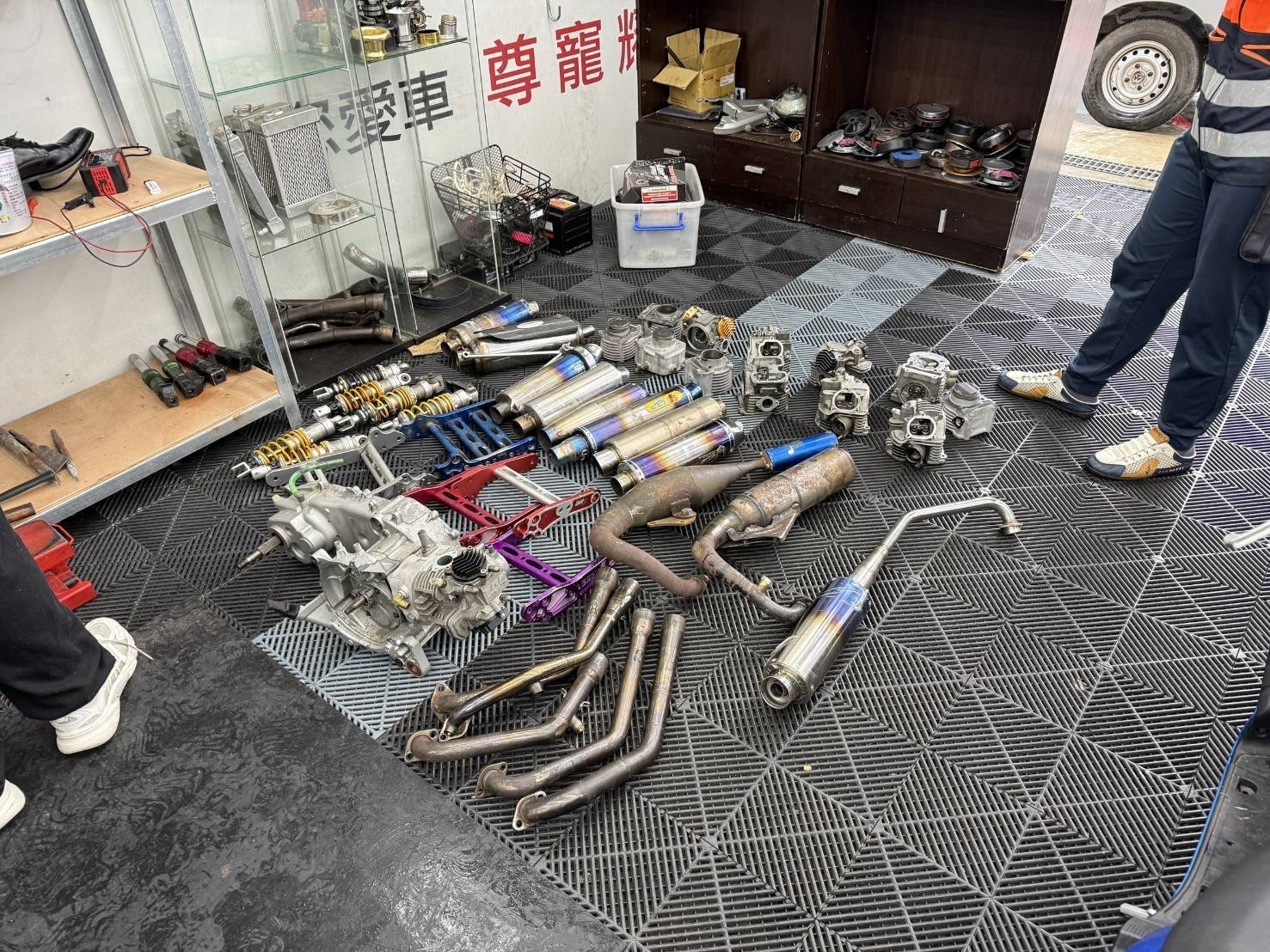 專案小組於車行內查獲大量改裝排氣管、避震器、引擎及車體零件等證物,作為追查飆車集團及非法改裝行為的重要依據。(圖/記者張家燁翻攝)