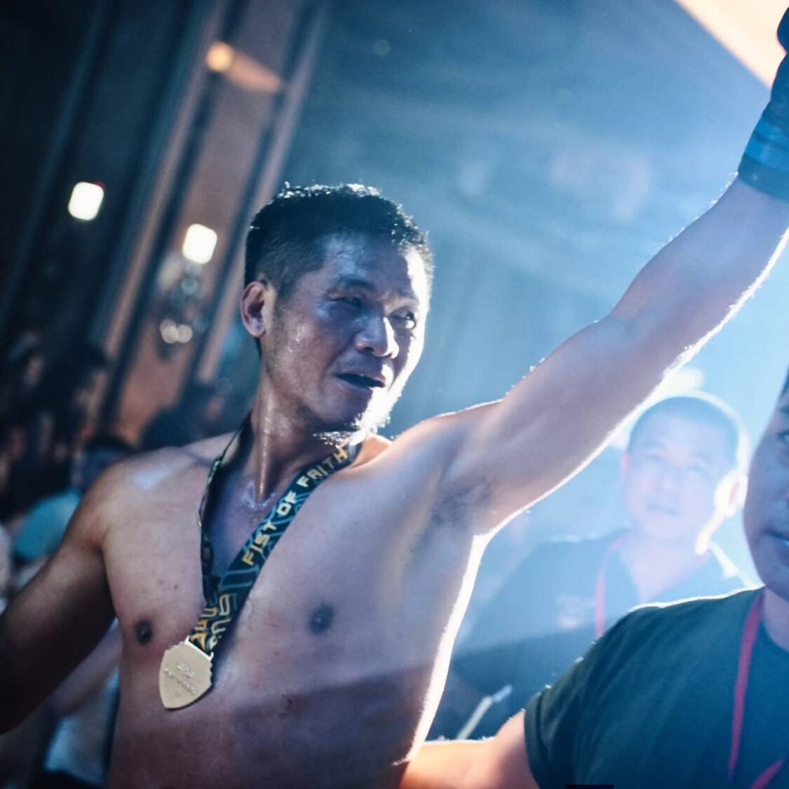 王信助於拳願賽事奪勝後高舉手臂慶祝,並佩戴獎牌接受全場喝采,至今保持11戰全勝、不敗紀錄。(圖/王信助提供)