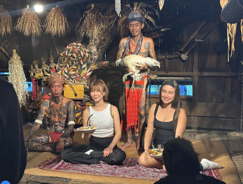 Miring 是砂拉越原住民族重要祭祀與祈福儀式，透過向神靈、守護靈與祖先獻上供品，祈求平安、健康與成功。Estelle 與 Safron 接受了 Miring 祈福儀式的祝福。(圖/AXN 提供)