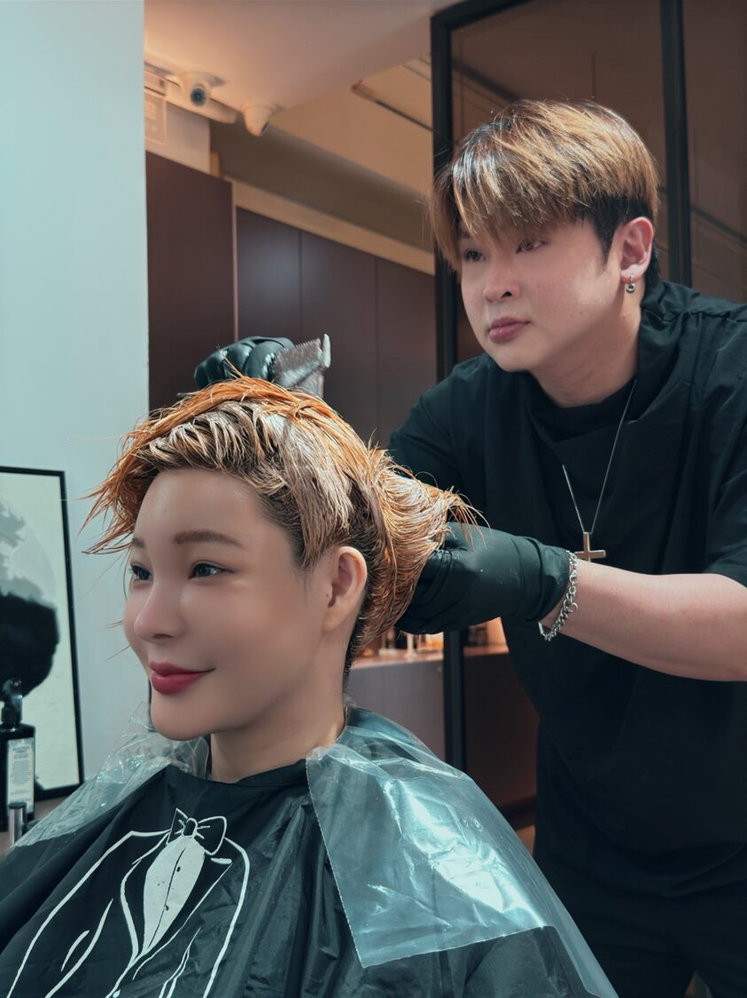 孟慶而(前)演出前特別整理髮色,由專業設計師Hero(後)進行染護,為舞台造型提前準備。(圖/法林髮藝提供)