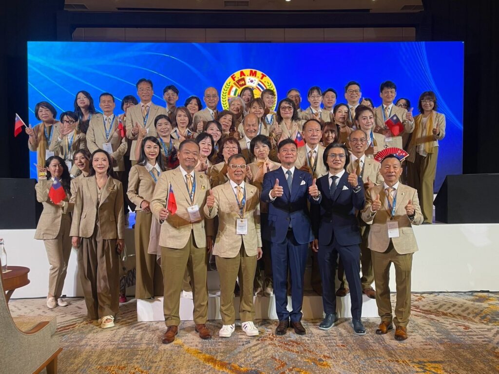 臺灣代表團全員穿著專業隊服，於「第 29 屆亞洲洋服同業聯盟大會」舞台上合影留念。（圖／臺北市西服商業同業公會提供）