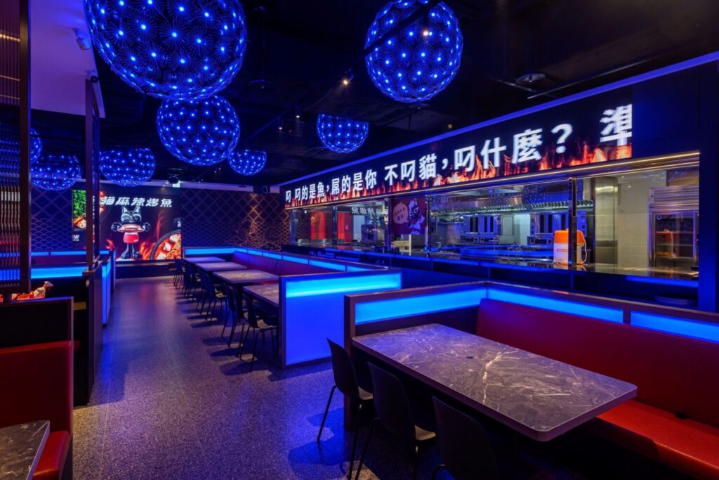 「叼貓 麻辣烤魚」以潮流燈光與開放式空間打造聚餐場景,結合美食、音樂與社交體驗。(圖/業者提供)