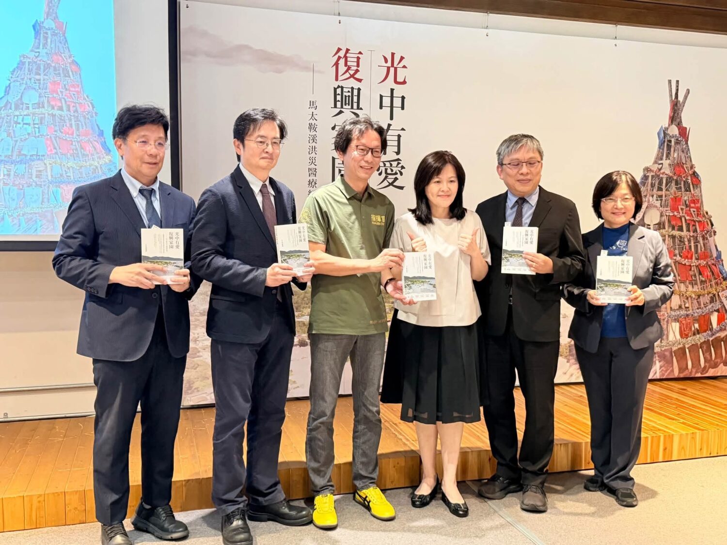 記者會貴賓們手持《光中有愛復興家園——馬太鞍溪洪災醫療紀實》合影,透過文字與影像保存馬太鞍溪洪災第一線醫療應變的珍貴經驗。(圖/記者張家燁翻攝)