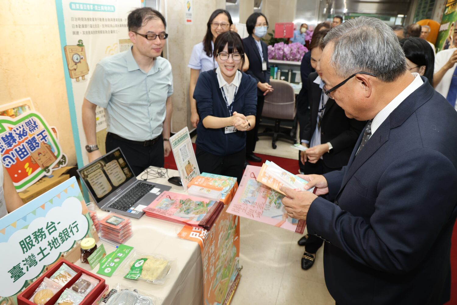照片說明:土地銀行80周年,行史檔案展結合公益市集活動,土地銀行總經理張志堅(右)聆聽同仁說明行史中英雙語摺頁設計,接軌國際客群 (圖/ 記者 劉其昌 翻攝)。。。