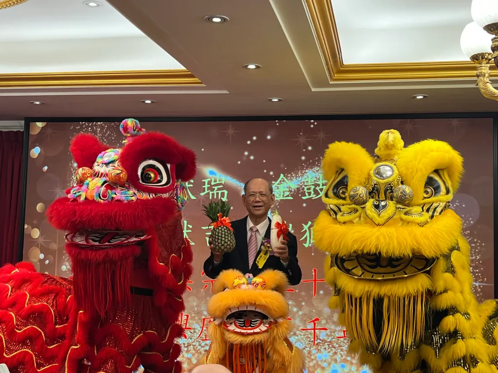台北市盧氏宗親會50週年會慶,理事長盧景鎮(中)與祥獅合影,手持象徵吉祥的鳳梨與好彩頭,為慶典增添喜氣,寓意宗親會會務興隆、世代傳承。(圖/記者薛秀蓮拍攝)
