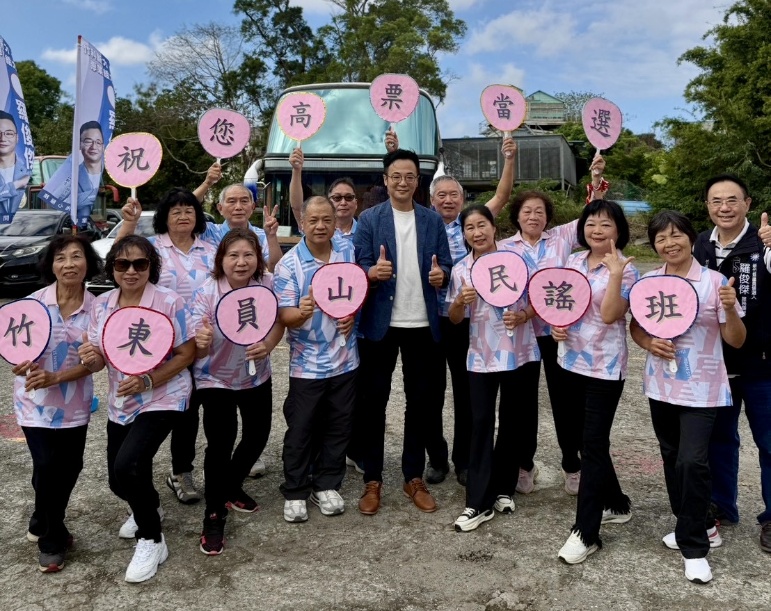 羅俊傑與竹東員山民謠班成員合影，成員手持「祝您高票當選」字牌，表達祝福。（圖/主辦單位提供）